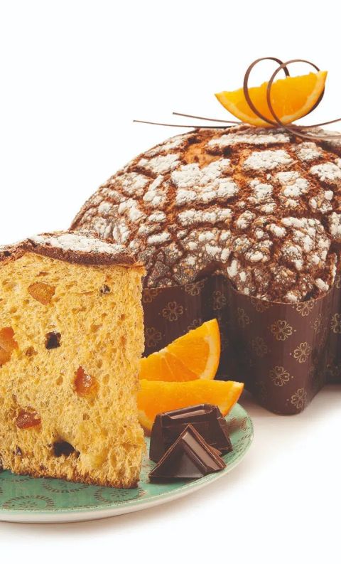 Dove-shaped Italian panettone cake dusted with powdered sugar, sliced to reveal candied fruit, served with orange wed...