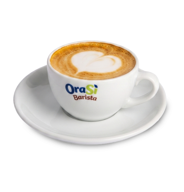 White cappuccino cup with heart-shaped latte art, labeled "OraSì Barista," on a matching saucer against a white backg...
