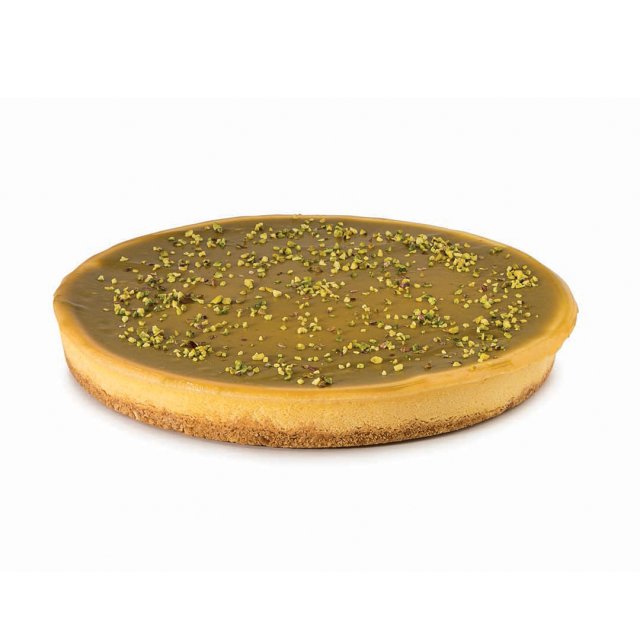 Round tart with a smooth caramel glaze top, biscuit-like crust, and crushed pistachios sprinkled over the surface.