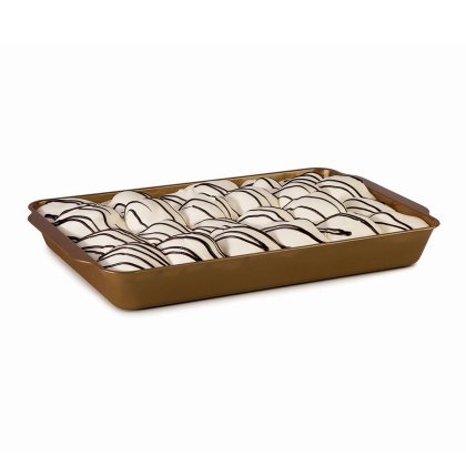 Rows of white-frosted pastries drizzled with dark chocolate lines, arranged in a gold rectangular baking tray.