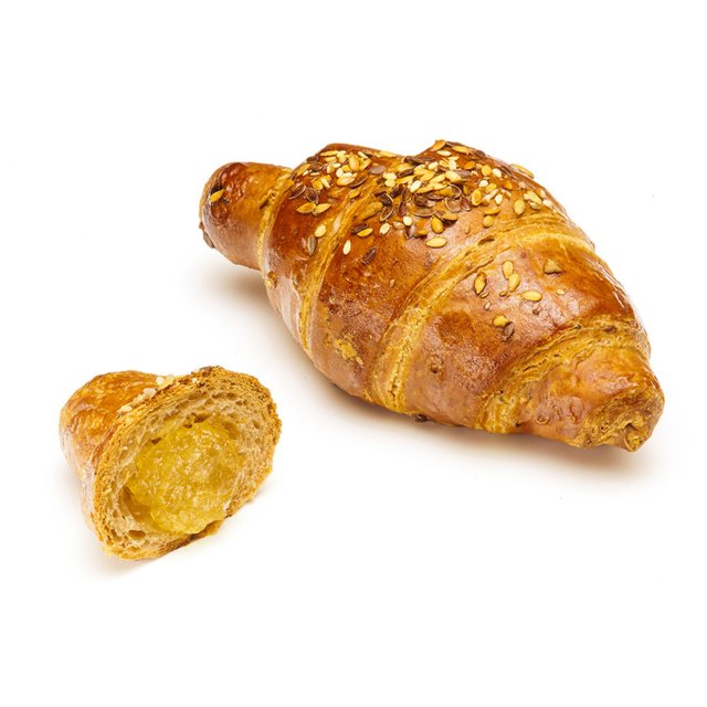 Golden multigrain croissant topped with seeds, with a smaller cut piece revealing a soft yellow filling, on a white b...