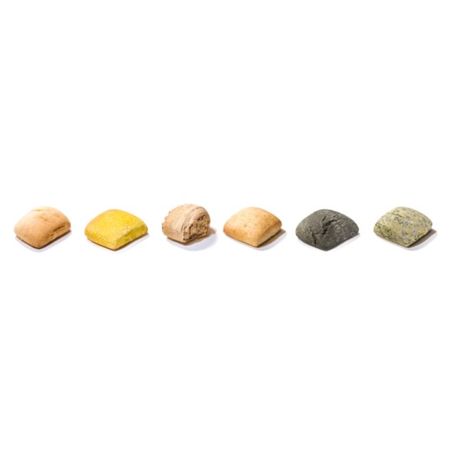 Six small square bread rolls in a row, varying in color from beige and yellow to charcoal black and green on a white ...