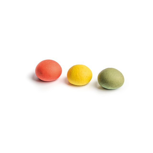 Three round, textured candies in red, yellow, and green, arranged in a row on a white background.