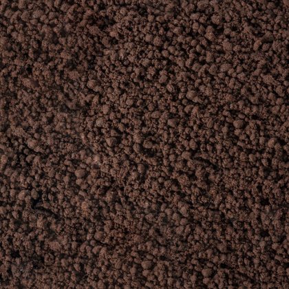 Close-up of a dark brown, crumbly textured surface resembling coarse soil or ground coffee grounds.
