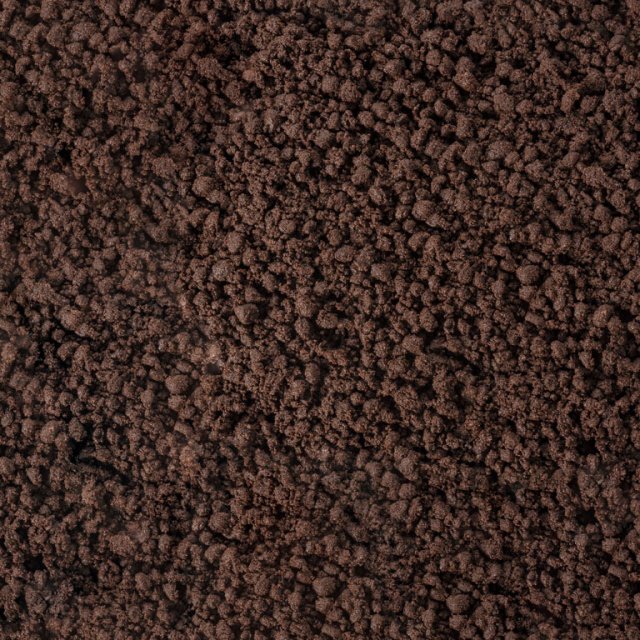 Close-up of a dark brown, crumbly textured surface resembling coarse soil or ground coffee grounds.