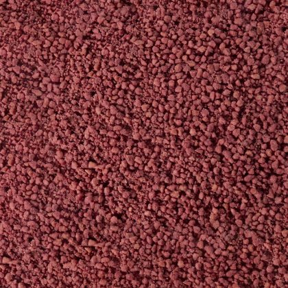 Close-up texture of coarse dark reddish-brown granules or powder, resembling clumped mineral or spice grains.