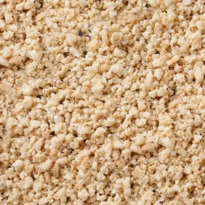 Close-up of pale beige crumbly granules with a coarse, crumb-like texture covering the entire frame.