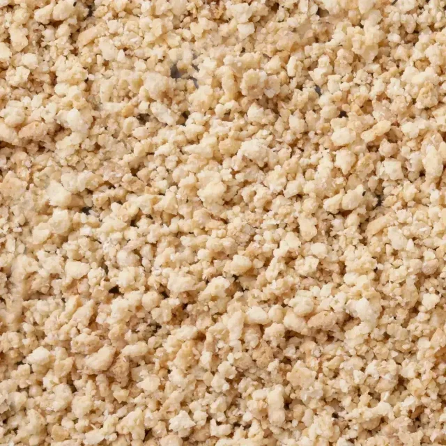 Close-up of pale beige crumbly granules with a coarse, crumb-like texture covering the entire frame.
