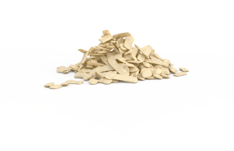 A pile of irregularly shaped beige plastic or wax flakes on a plain white background.