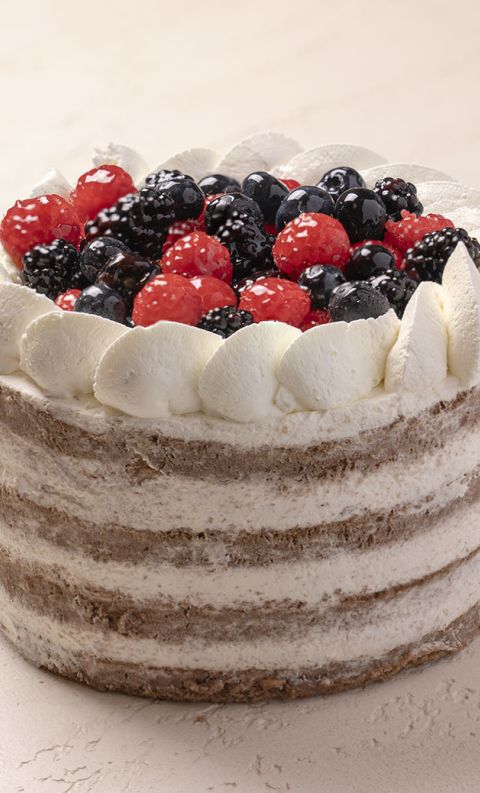 Naked layer cake with whipped cream frosting between thin sponge layers, topped with fresh raspberries, blackberries,...