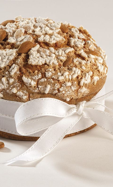 Round Italian amaretto cake topped with cracked sugar glaze and almonds, tied with a white ribbon bow.